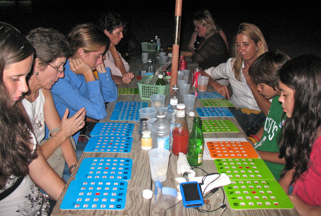 Bingo players at a table concentrating on their Bingo cards